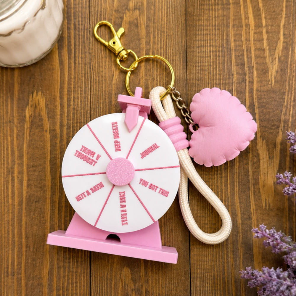Pink keychain with a wheel and heart-shaped charm on a wooden surface